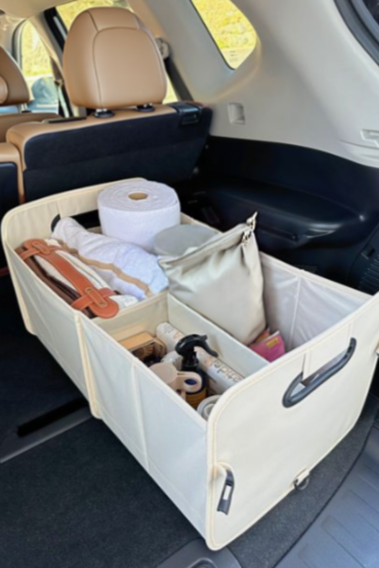 Beige car trunk organizer with multiple compartments holding essential car items like paper towels, cleaning supplies, and a blanket, showcasing an organized car interior.