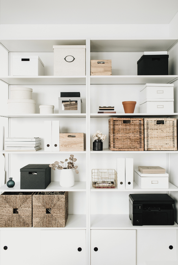 A well-organized shelving unit with various storage boxes, baskets, and decorative items, showcasing effective storage and organization solutions for a neat and tidy space.